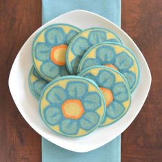 four blue and yellow flower cookies on a white plate next to a blue cloth napkin