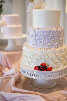 three tiered wedding cake with white frosting and red car decoration on the top