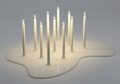 a group of lit candles sitting on top of a white table next to each other