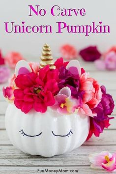 a white pumpkin decorated with pink flowers and a unicorn's horn on the top