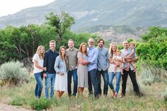 a group of people standing next to each other in a field with mountains in the background