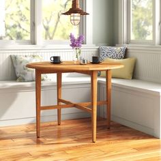 a wooden table with two cups on it in front of a white window sill