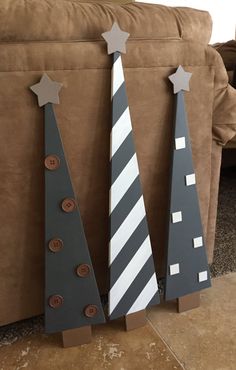 three wooden christmas trees sitting next to each other on top of a brown couch in a living room