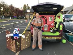 a woman standing in front of a car with an assortment of items on the back