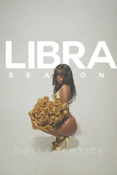 a woman holding a bunch of flowers in front of a white wall with the word libra on it