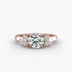 a rose gold engagement ring with three stones on the side and an accent diamond in the center