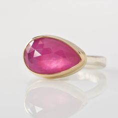 a pink stone ring sitting on top of a white surface