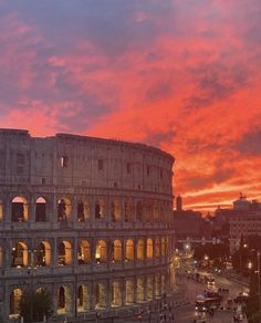 the roman colossion is illuminated at night with bright red clouds in the background