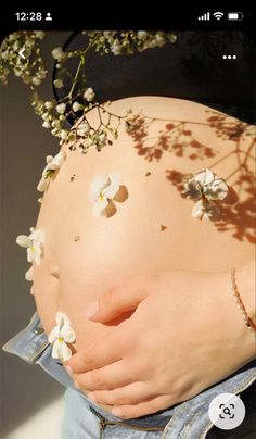 a pregnant woman's stomach with flowers on it and her hands in the belly