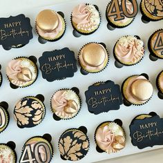 a box filled with lots of cupcakes covered in gold and black frosting