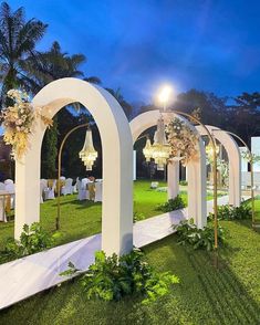 an outdoor wedding setup with flowers and chandeliers on the grass at night time