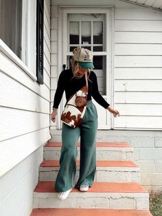 a woman is walking down the steps in front of a house with her hat on