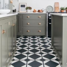 a kitchen with black and white tile flooring and gray cabinetry, along with an oven