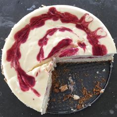 a cake with white frosting and red swirls sitting on top of a black plate