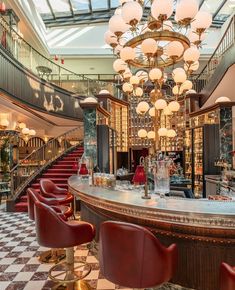 an elegant bar with red chairs and chandelier