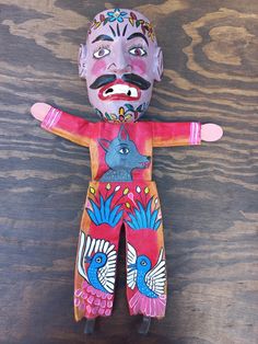 a colorfully painted doll sitting on top of a wooden table