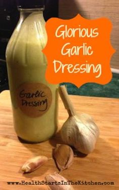 a bottle of garlic dressing sitting on top of a wooden table next to an onion