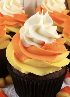 cupcakes with orange and white frosting sitting on top of candy corn stalks