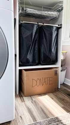 a cardboard box with two black bags sitting on top of it next to a washer and dryer