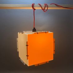 an orange and white object hanging from a wooden beam with red cords attached to it