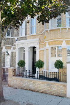 a large brick building with white windows and black iron railings on the sidewalk in front of it