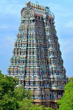 a tall tower with many colorful sculptures on it's sides and trees in the foreground