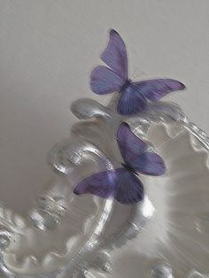 three purple butterflies sitting on top of a glass plate