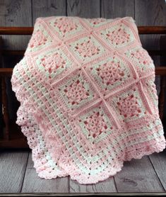 a pink crocheted blanket sitting on top of a wooden chair