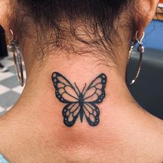 a woman's neck with a butterfly tattoo on the back of her neck,