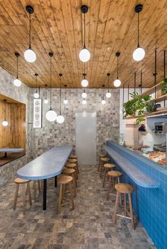 an indoor dining area with wooden ceiling and tile flooring, round lights hanging from the ceiling