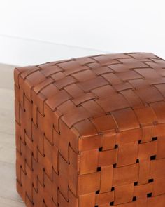 a brown basket sitting on top of a hard wood floor next to a white wall