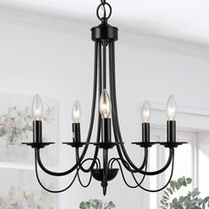 a black chandelier with five lights hanging from it's centerpiece in a living room