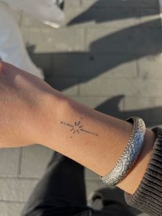 a person's arm with a small star tattoo on it