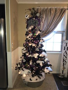 a decorated christmas tree in the corner of a room next to a window with halloween decorations on it