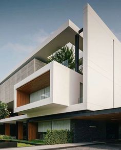 an architecturally designed house in the middle of a street with trees and bushes on both sides