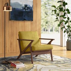 a yellow chair sitting on top of a wooden floor next to a plant in a living room