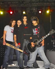 three young men standing next to each other with guitars in front of them on stage