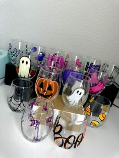 many glasses with halloween designs on them sitting on a table next to other glassware