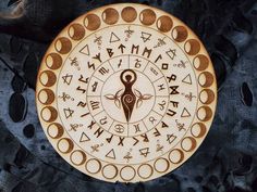 a circular wooden plaque with various symbols on it