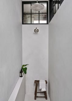 a white bathroom with a wooden bench in the corner