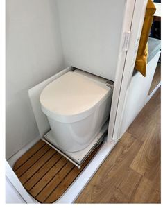 a white toilet sitting on top of a wooden floor