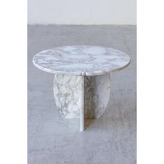 a white marble coffee table sitting on top of a cement floor