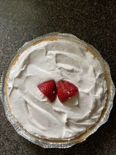 two strawberries are placed on top of the whipped cream in a pie crust, which is ready to be eaten