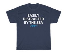 a navy t - shirt that says easily distracted by the sea on it's chest