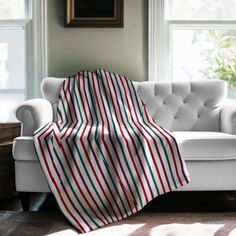 a white couch with a red, green and blue striped blanket on top of it