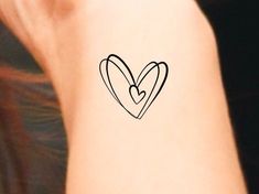 a small heart tattoo on the back of a woman's left arm and wrist