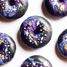 six doughnuts with different designs on them are arranged in a row and one has gold sprinkles