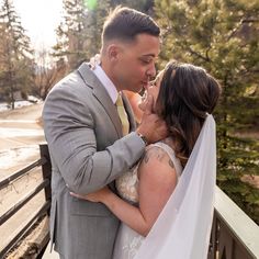 a bride and groom kissing on a bridge