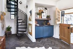 a kitchen with blue cabinets and stairs in the background, next to an open door