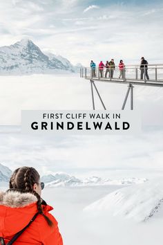 a group of people standing on top of a snow covered mountain next to a bridge